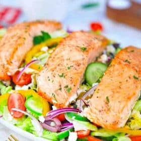 greek salmon salad on a plate topped with perfectly cooked salmon filets