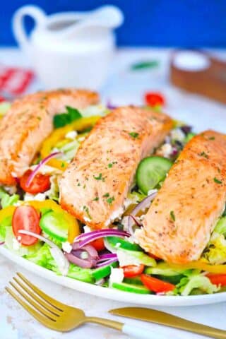 greek salmon salad on a plate topped with perfectly cooked salmon filets