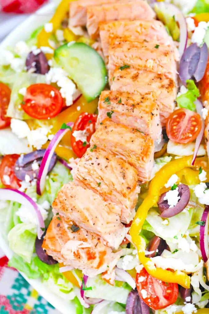 sliced salmon filet on top of Greek salad