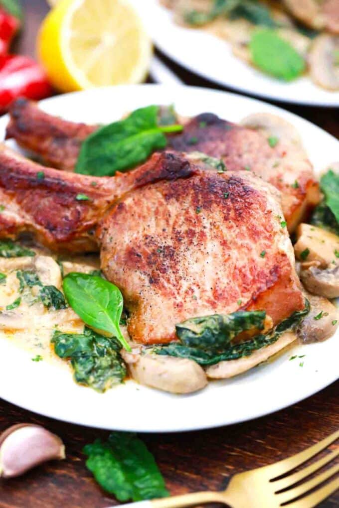 creamy garlic pork chops on a plate with some spinach