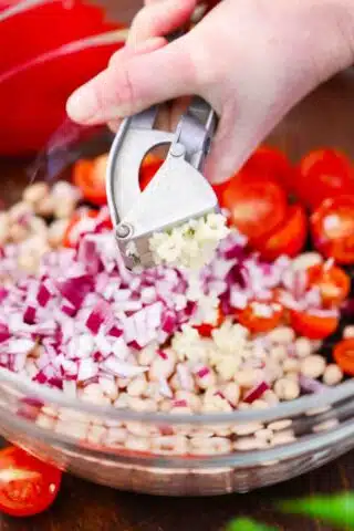 adding garlic to a bowl of ingredients