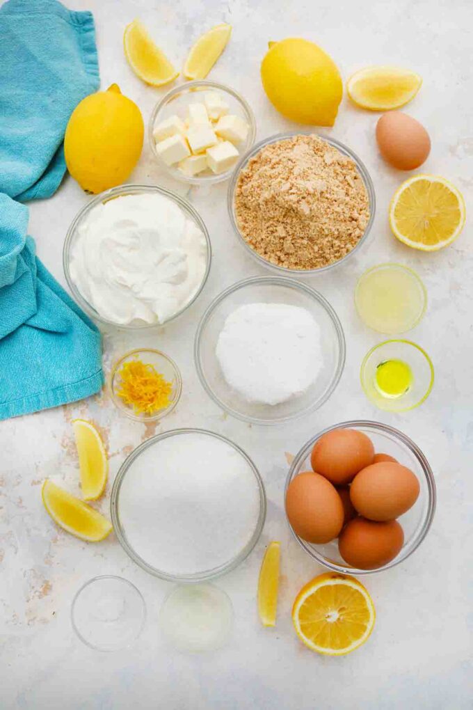 overhead shot of cookie crumbs lemons eggs ricotta sugar butter in bowls on a table