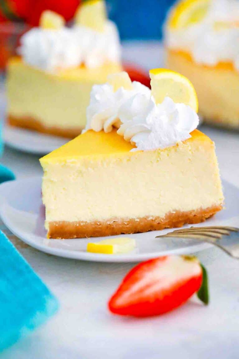 close shot of a slice of lemon ricotta cheesecake topped with whipped cream