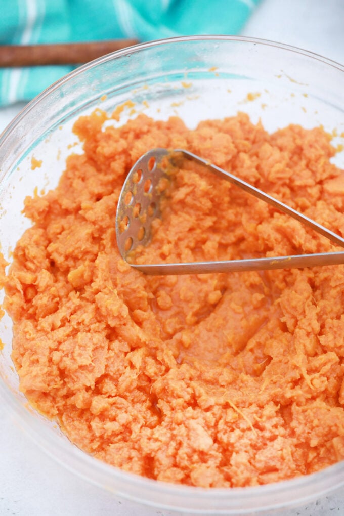Mashing sweet potatoes in a bowl.