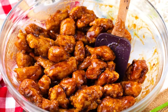 Coating fried chicken pieces in General Tso sauce.