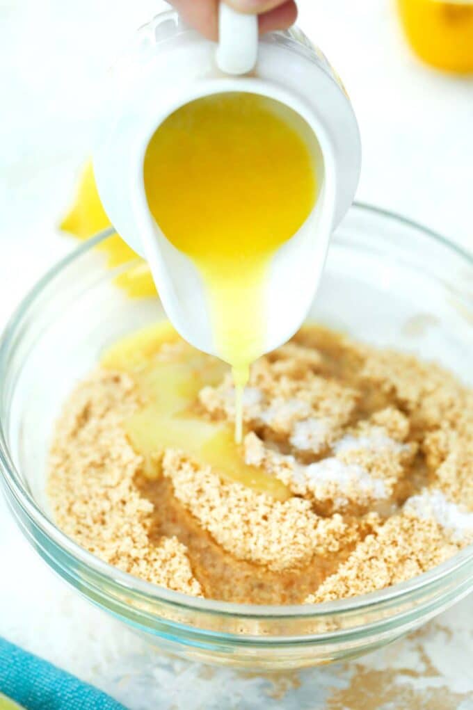 pouring butter into a bowl with graham cracker crumbs and salt