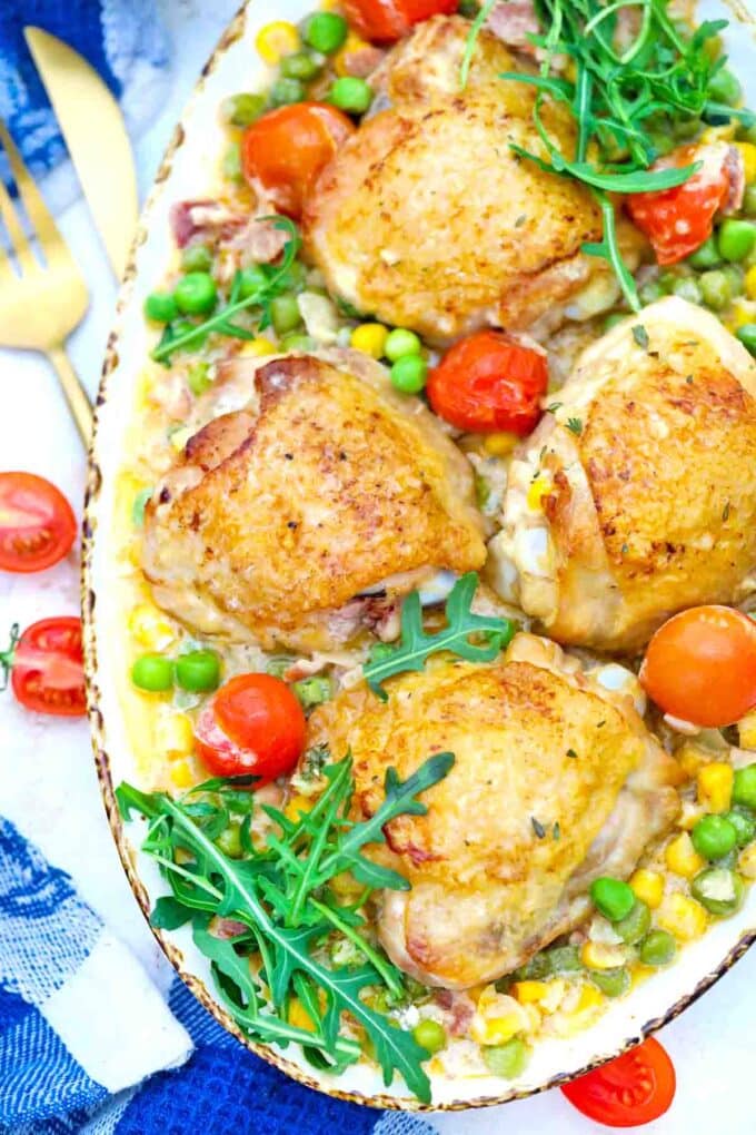 overhead shot of creamy corn chicken with cherry tomatoes and sweet peas