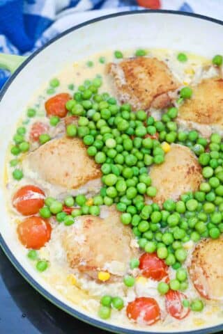 adding sweet peas to chicken thighs in a creamy sauce