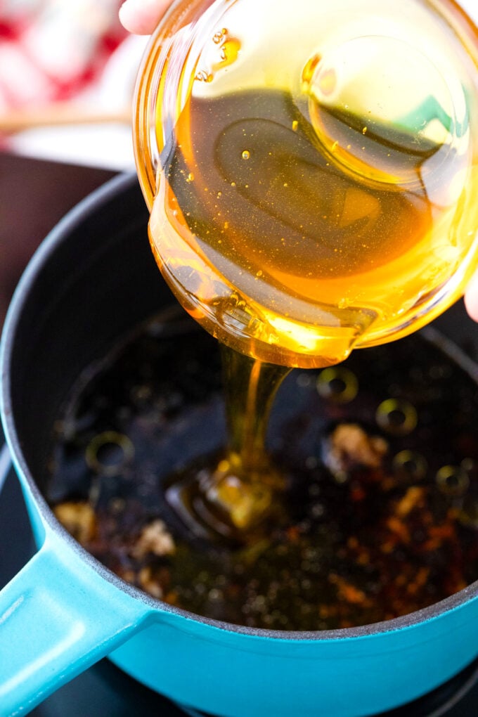 Adding honey to a saucepan to make honey garlic ginger sauce.
