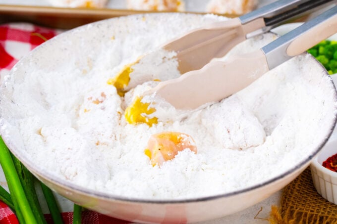 Tossing chicken pieces in cornstarch flour mix.