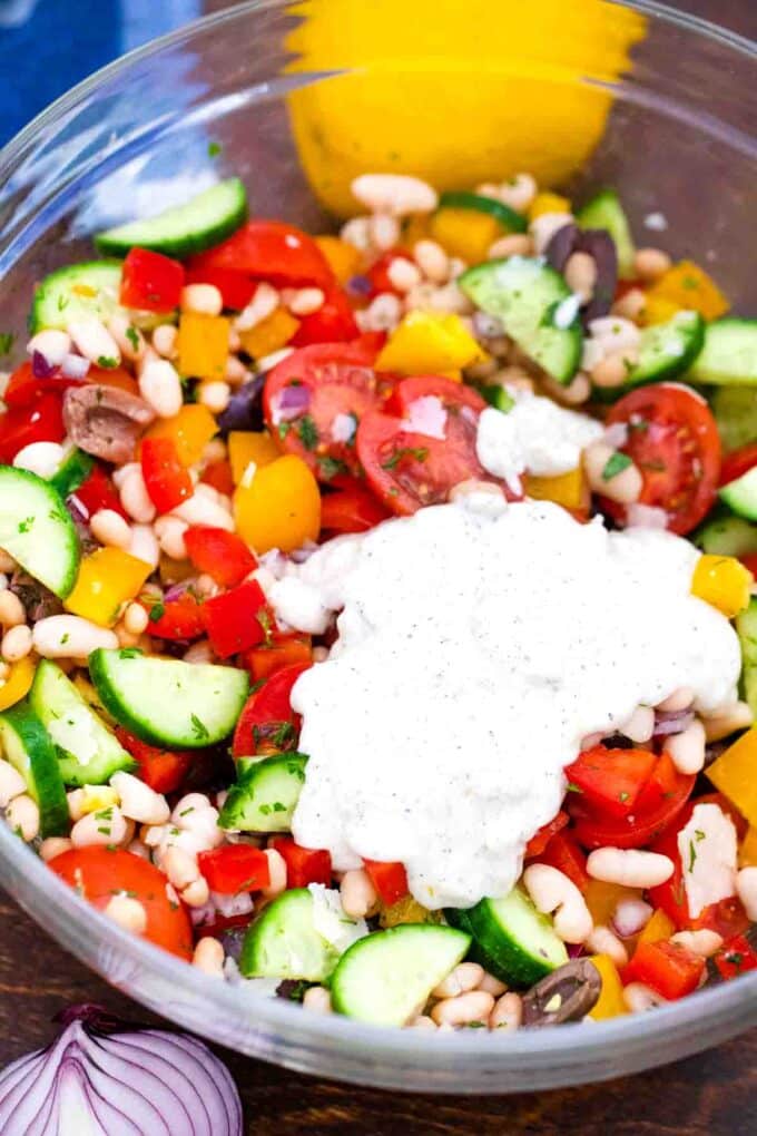 adding a creamy dressing to a veggie bean salad
