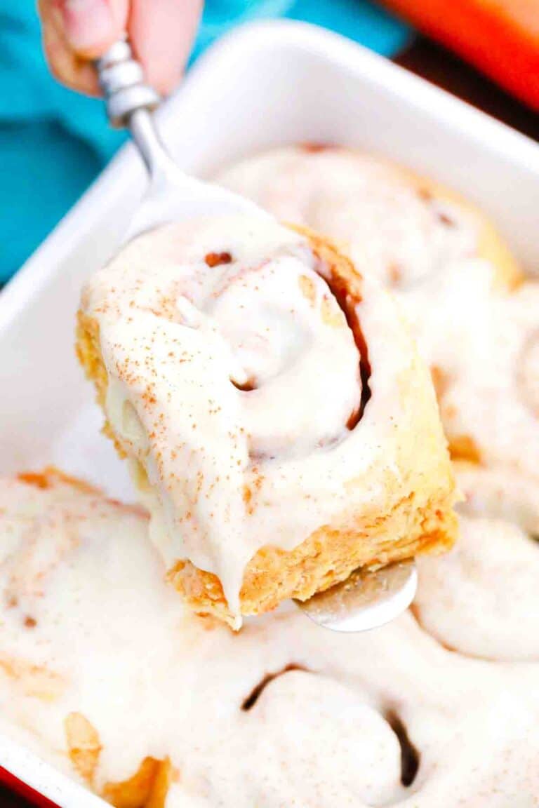 lifting a carrot cake cinnamon roll on a spatula