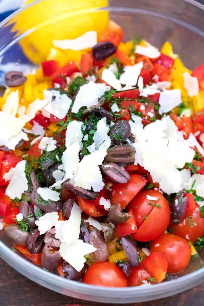 adding parmesan to a bowl of veggies and bean salad