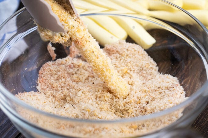 Coating cheese sticks in panko bread crumbs.