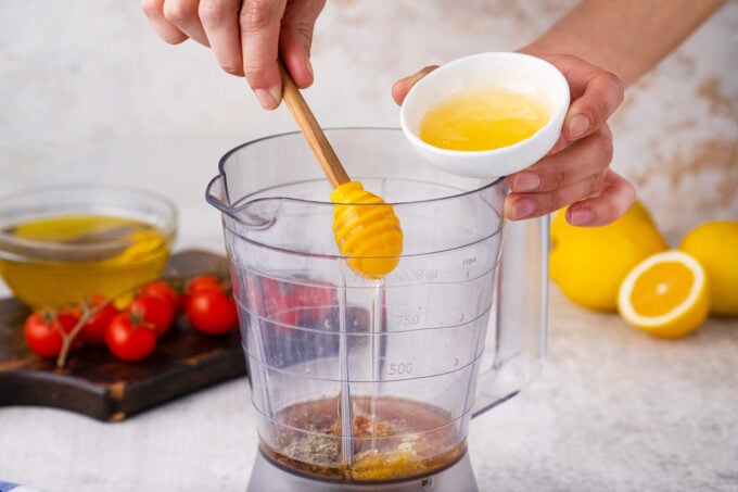 Adding Greek salad dressing ingredients to a blender.