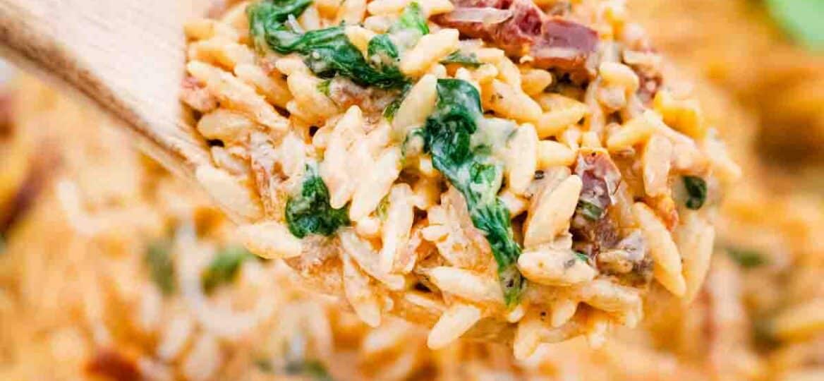 a wooden spoon filled with creamy tuscan orzo