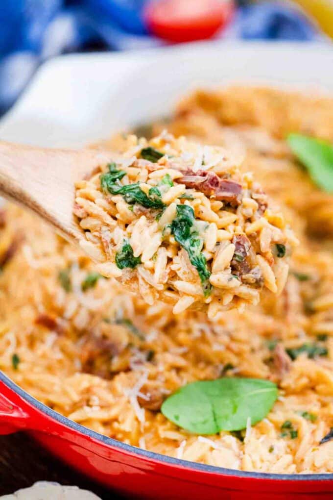a wooden spoon filled with creamy tuscan orzo