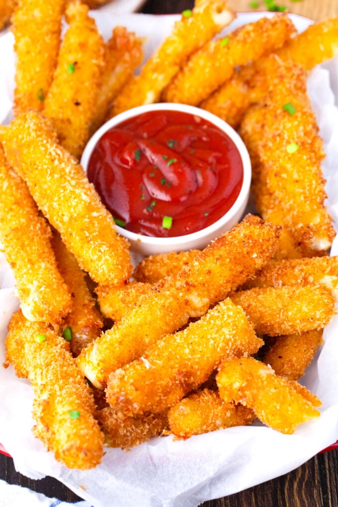 A plate of crispy fried cheese sticks with marinara sauce.