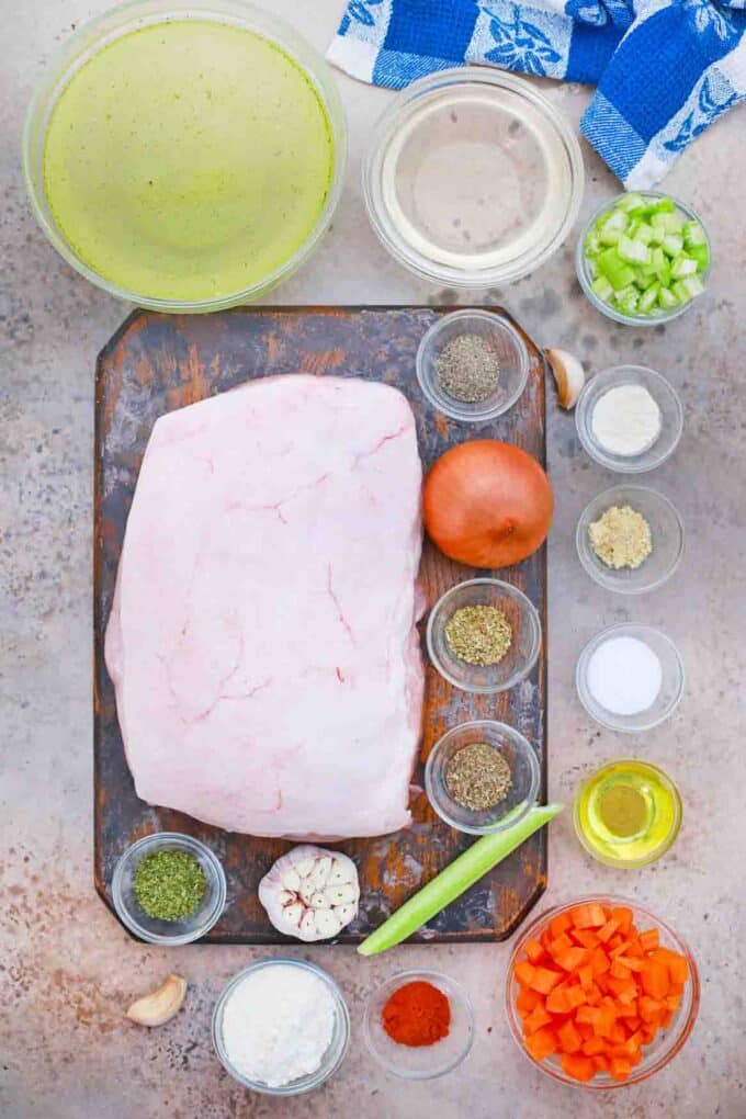 overhead shot of pork butt seasonings broth and veggies in bowls on a table