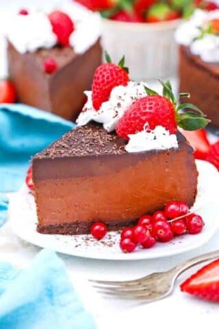 a slice of godiva chocolate cheesecake topped with whipped cream and strawberries