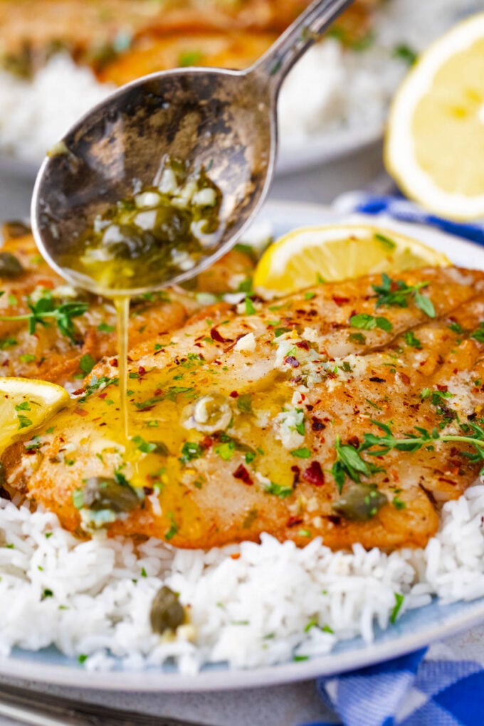 Drizzling lemon garlic sauce over swai fish.
