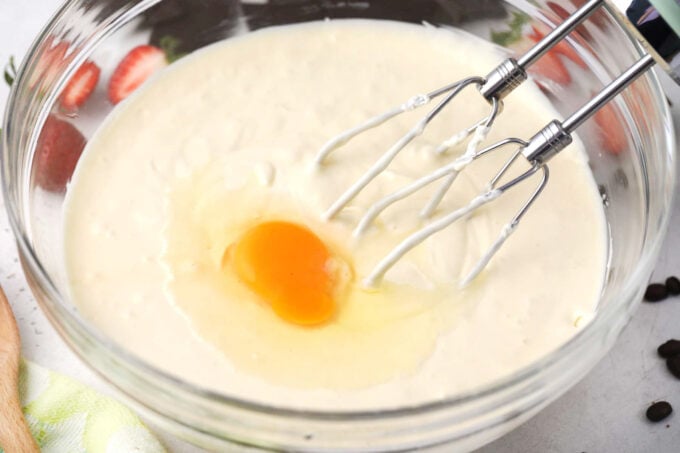 Whisking eggs into cheesecake batter.