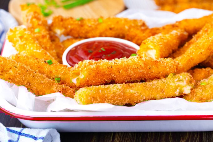 A tray of fried cheese sticks with marinara sauce.