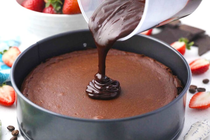 Pouring chocolate ganache on top of chocolate Godiva cheesecake.