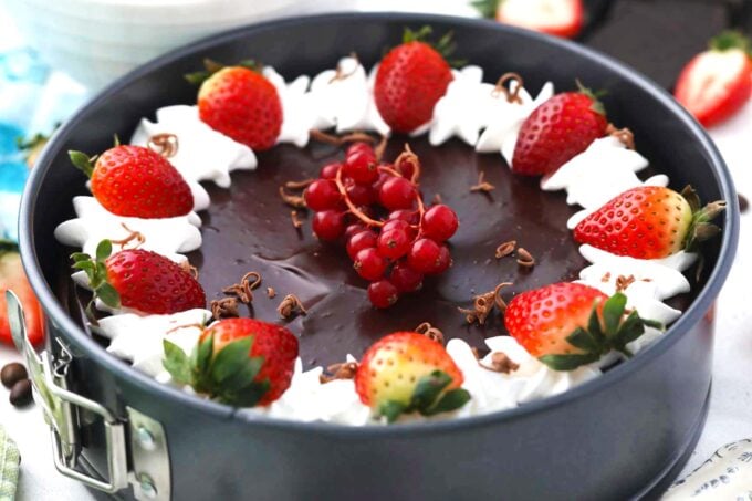 Godiva chocolate cheesecake garnished with whipped cream, strawberries, and red currant.