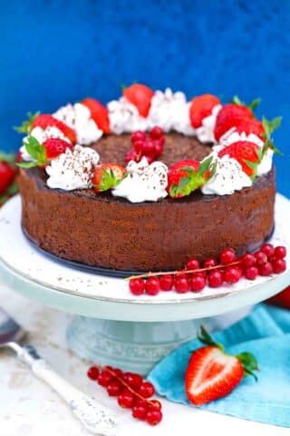 godiva chocolate cheesecake topped with chocolate ganache whipped cream and berries