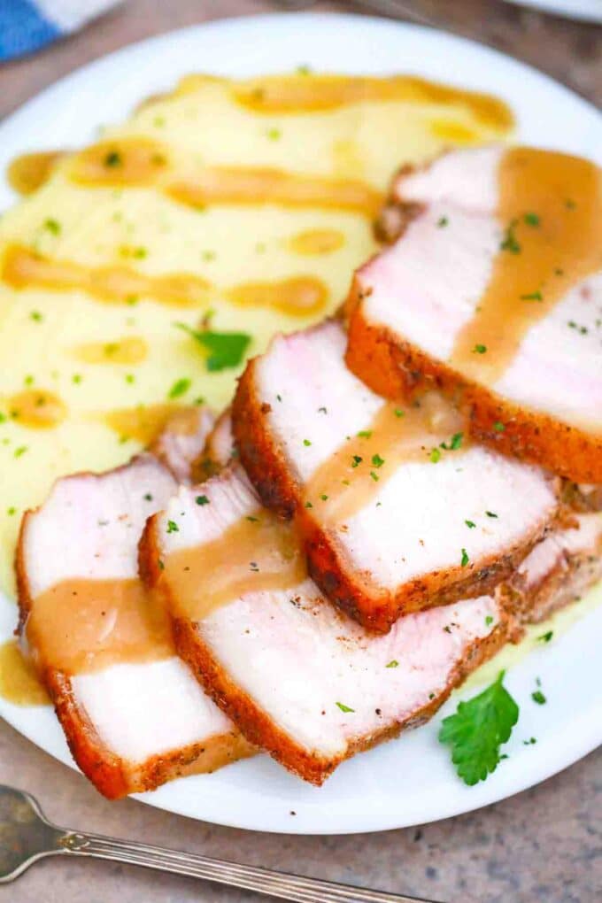 overhead shot of sliced crispy pork roast topped with gravy