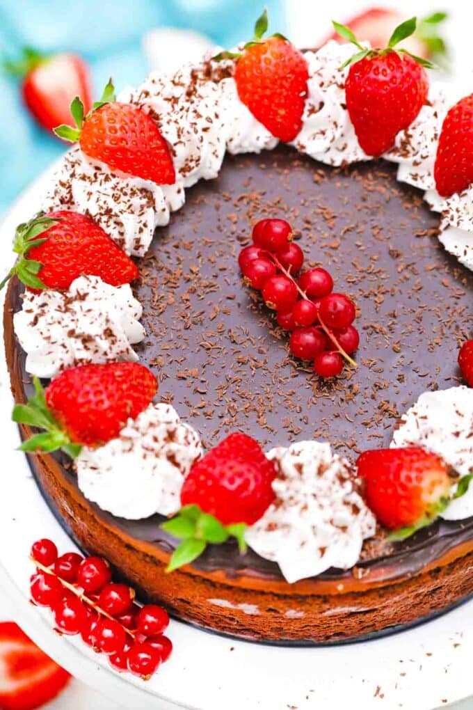overhead shot of godiva chocolate cheesecake topped with chocolate ganache whipped cream and berries