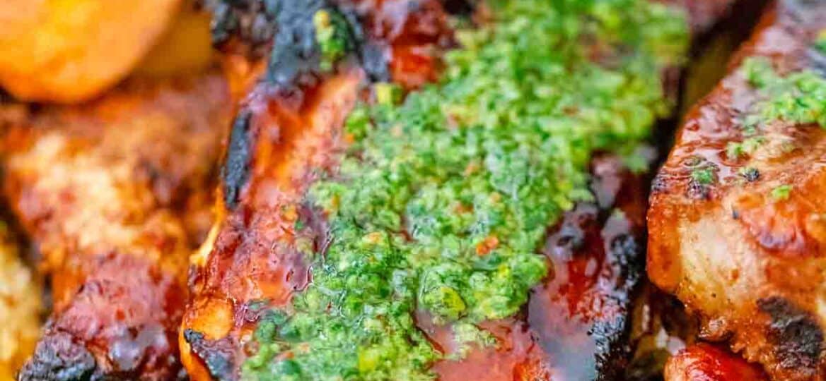 pouring chimichurri sauce over lemon chimichurri pork chops