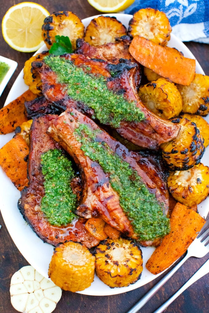 A platter of grilled lemon chimichurri pork chops with veggies.