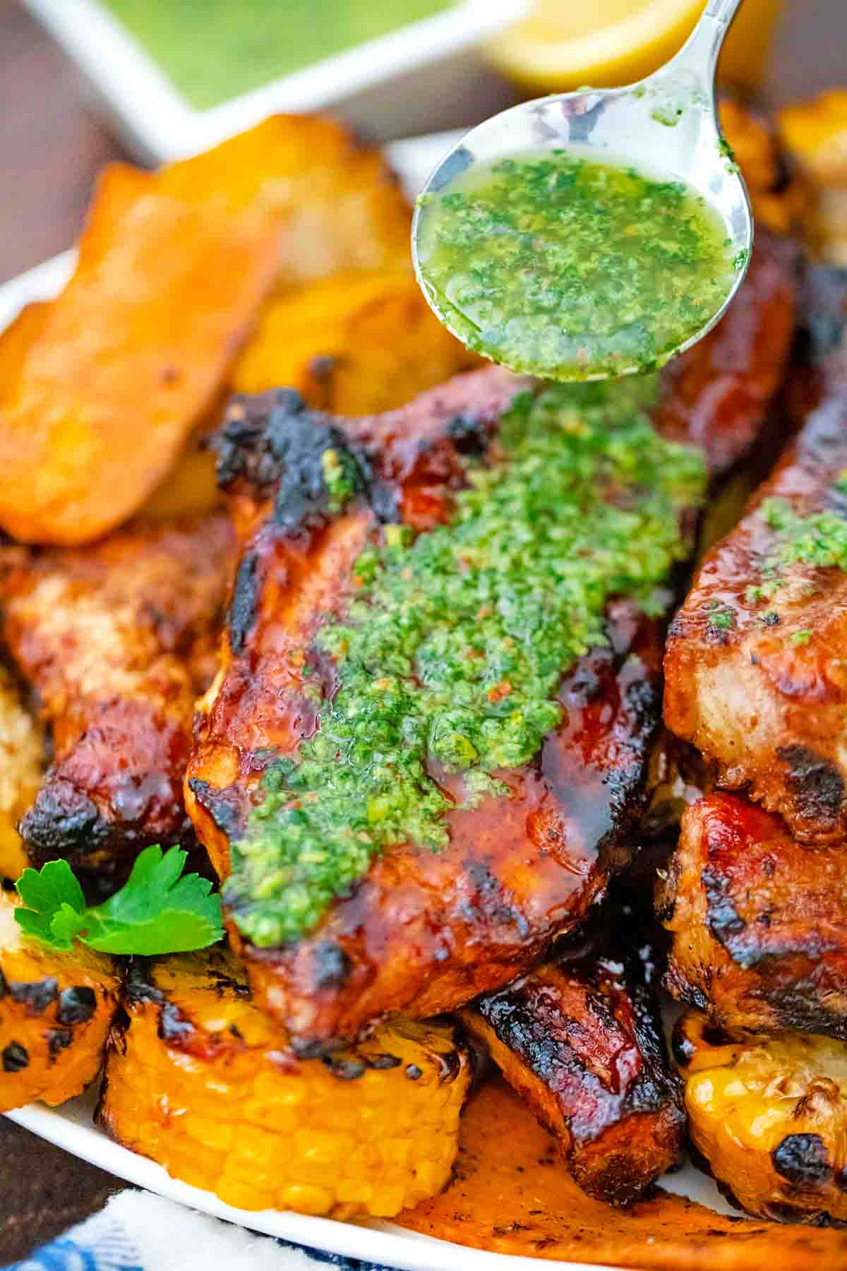 pouring chimichurri sauce over lemon chimichurri pork chops