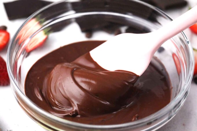 Stirring melted dark chocolate in a bowl.