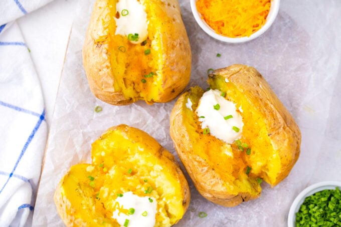 Three microwaved potatoes topped with sour cream and chives.