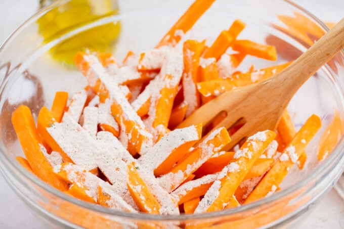 Tossing sweet potato fries with a seasoning mix.