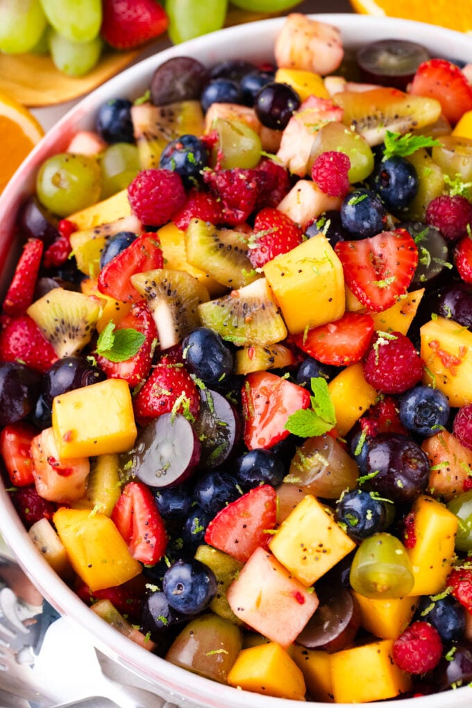 A bowl of fruit salad with honey lime poppy seed dressing.