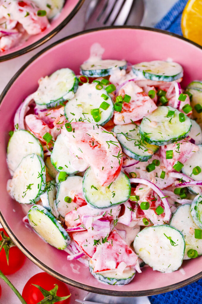 Creamy cucumber tomato salad with red onion and dill.