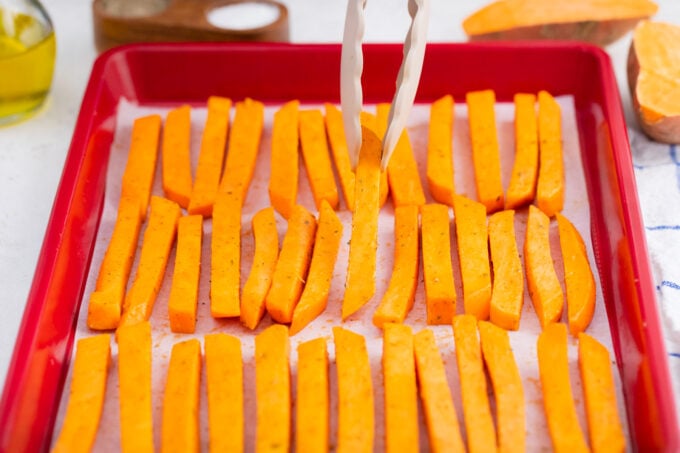 Arranging sweet potato fries on a baking sheet.