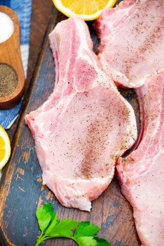 seasoning bene in pork chops on a wooden board