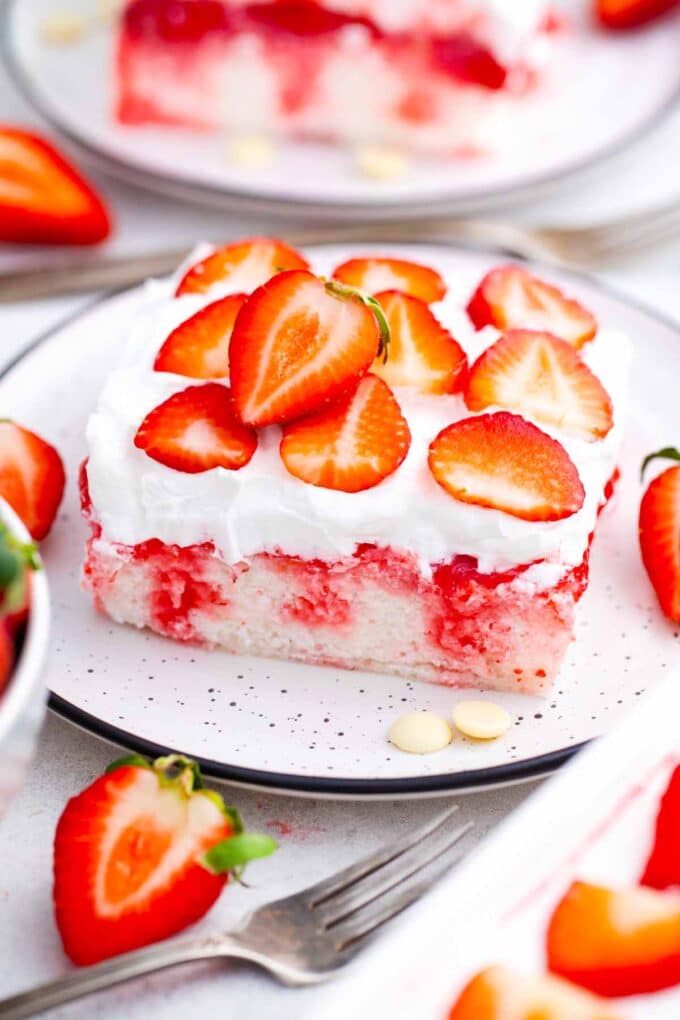 a slice of white strawberry poke cake with fresh strawberries