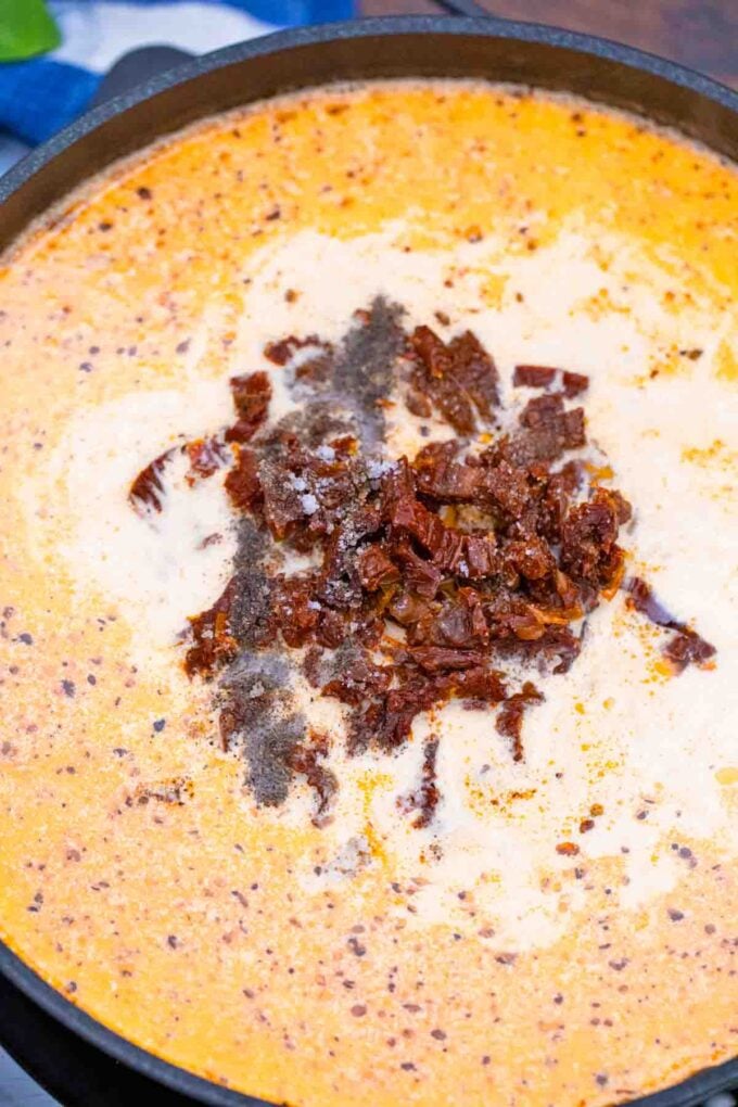 adding chopped sun dried tomatoes to creamy orzo