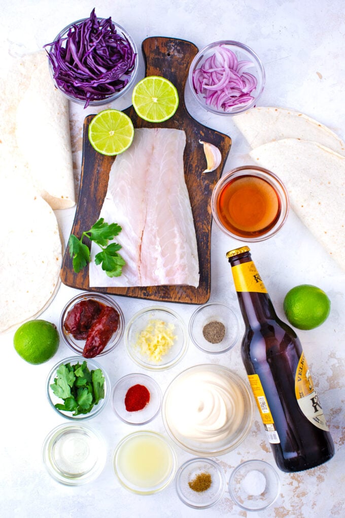 Overhead shot of Baja fish tacos ingredients arranged on a light surface.