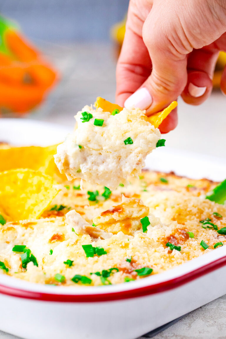 Scooping chicken Caesar dip with a corn chip.