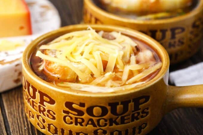 a bowl of instant pot french onion soup topped with a slice of french baguette and shredded gruyere cheese