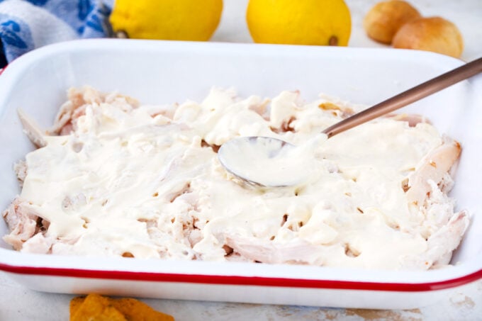 Layering chicken Caesar dip in a baking pan.
