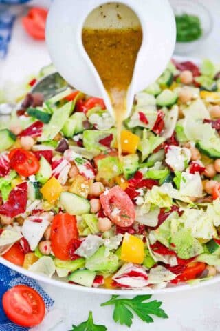 pouring dressing on top of chopped mediterranean salad