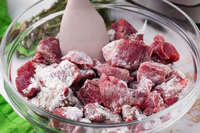 Coating beef pieces in flour.